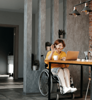 disability pension in Israel - smiling woman in wheelchair using laptop